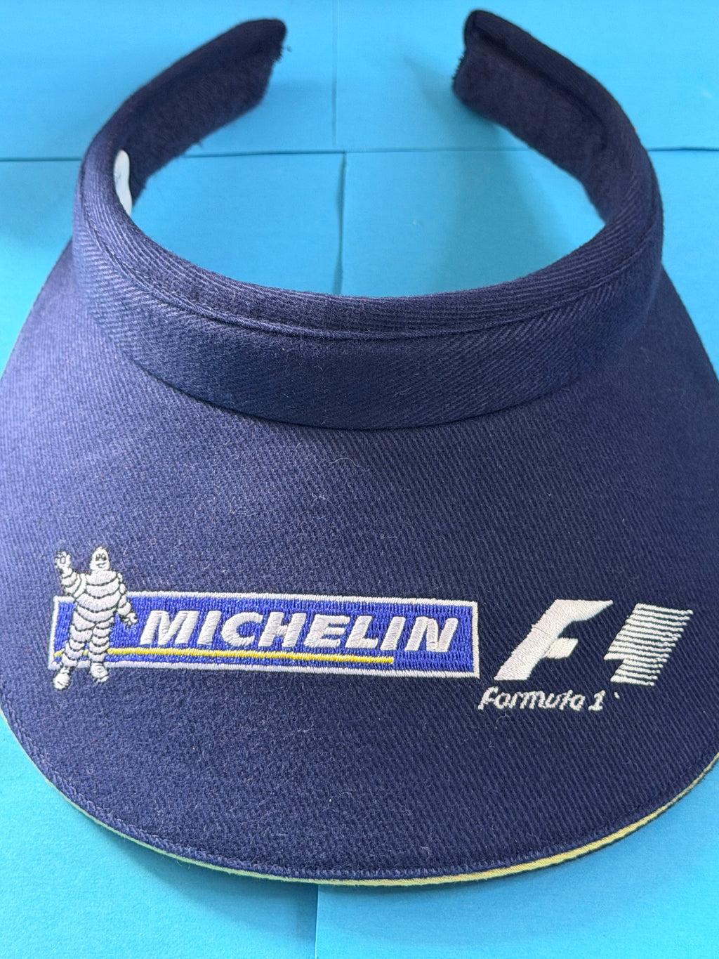 Gros plan sur les broderies Bibendum Michelin et Formula 1 de la visière vintage bleu marine.