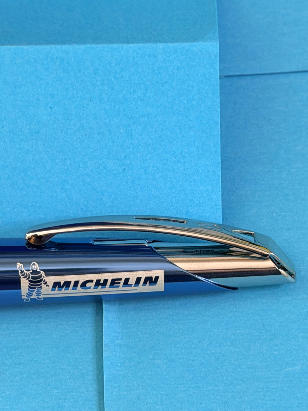 Détail du logo Michelin et Bibendum sur le corps du stylo bleu avec clip métallique chromé.