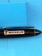 Gros plan sur le logo Michelin et Bibendum apposé sur le corps noir brillant du stylo.