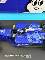 Gros plan sur le cockpit et la carrosserie de la Formule 1 Michelin avec pilote casqué et décoration rare Bibendum bleu.