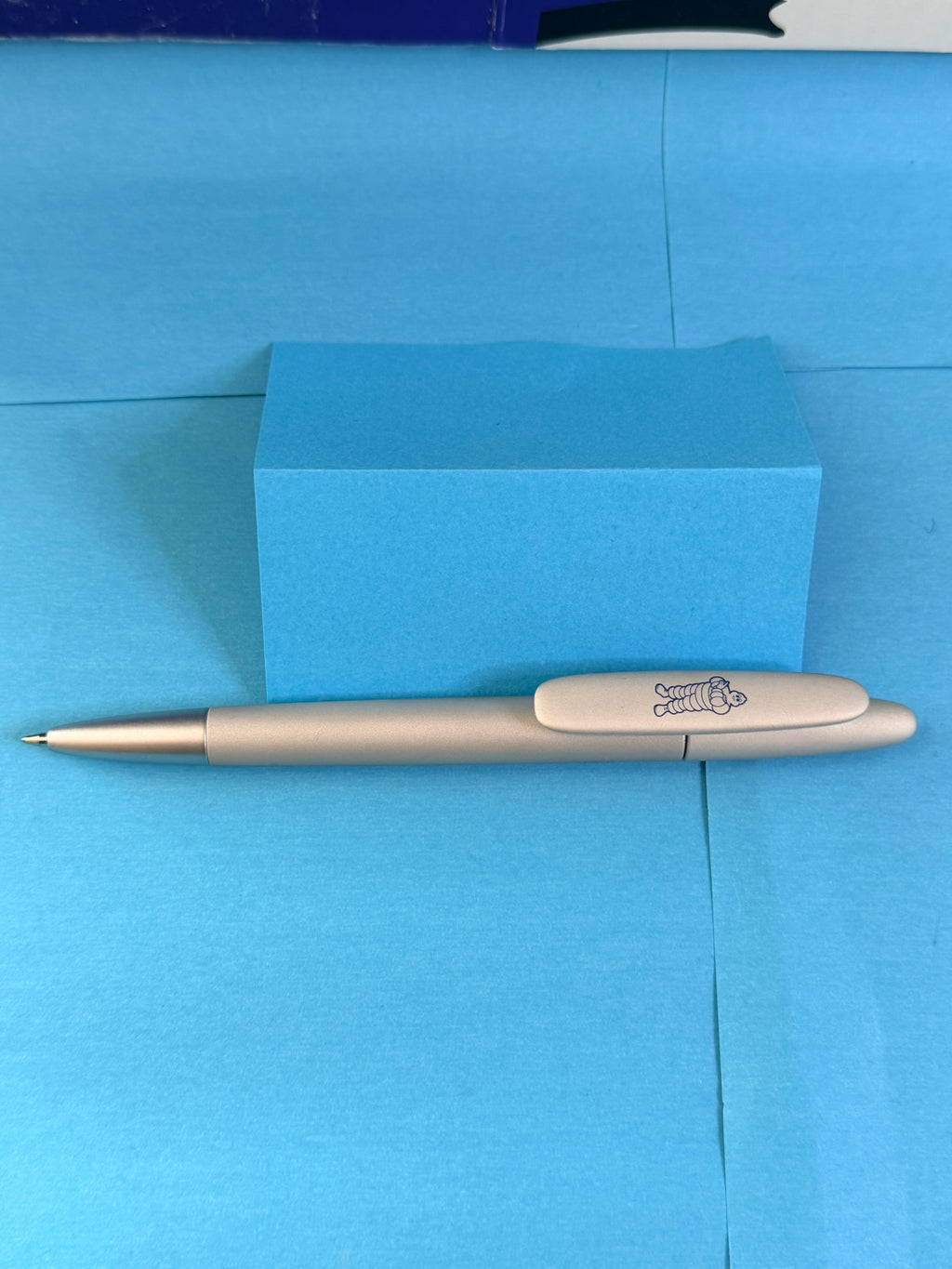 Stylo Michelin gris avec Bibendum bleu sur le clip, modèle publicitaire avec mine neuve.