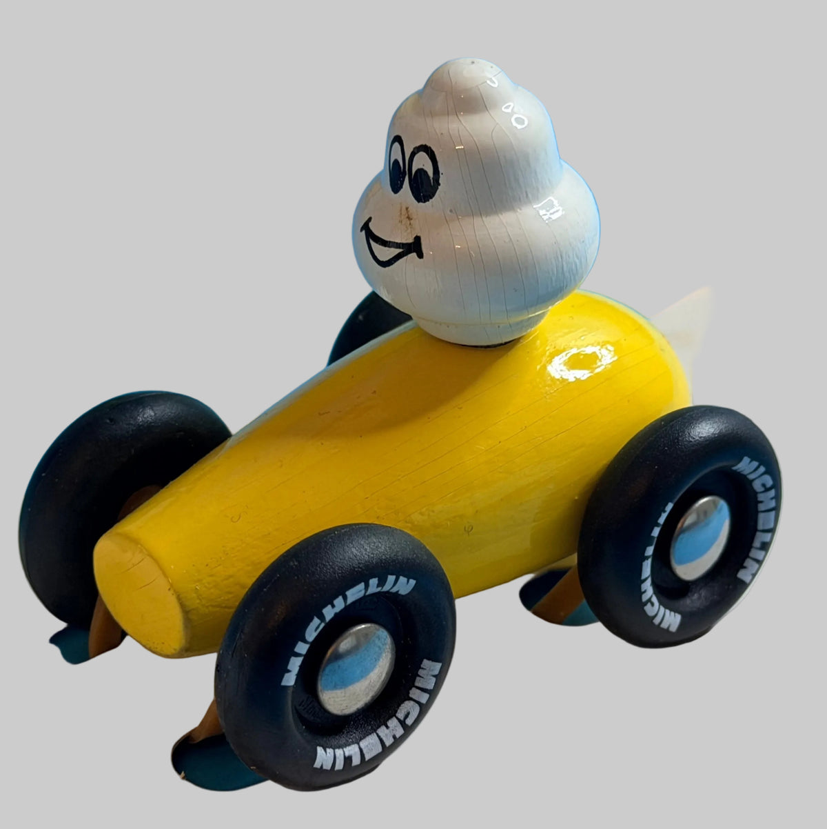 Voiture jaune Michelin Village avec Bibendum au volant, vue trois-quarts