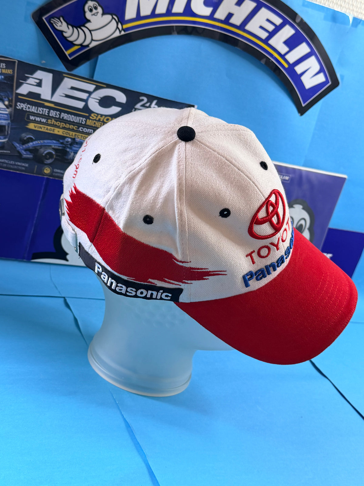 Vue trois quarts de la casquette Toyota Panasonic Racing Formule 1 avec broderies latérales et visière rouge.