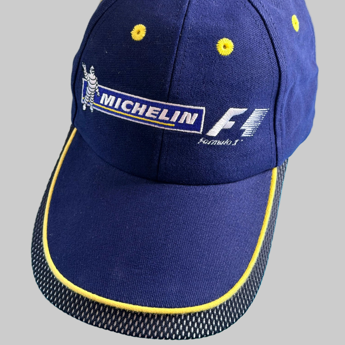 Casquette Michelin Formula 1 neuve bleu marine avec broderies Michelin Bibendum et F1 et visière bordée de jaune.