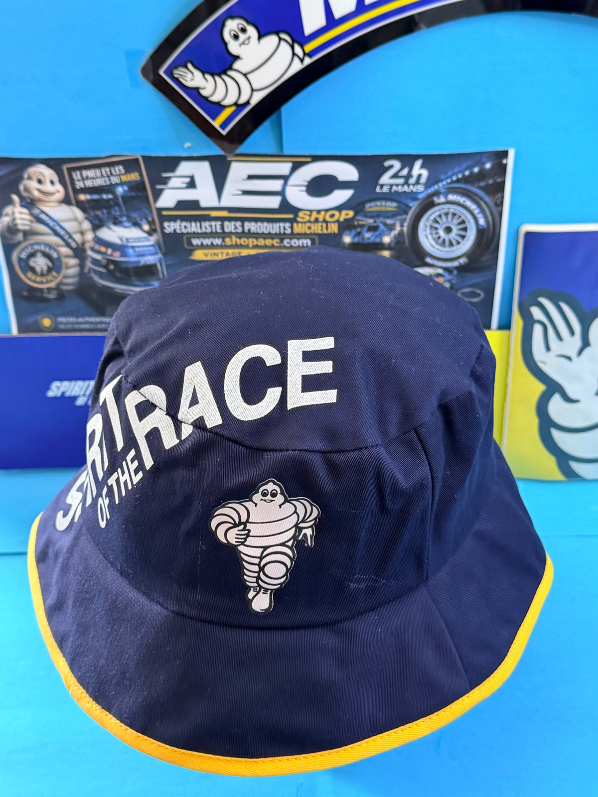 Bob Michelin Formula 1 neuf avec Bibendum et inscription Spirit of the Race, bleu marine et jaune.