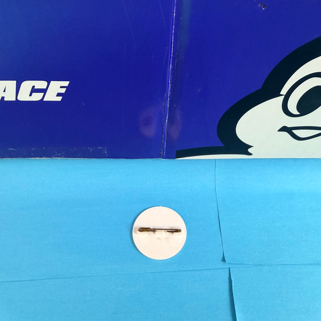 Vue détaillée du dos du badge Michelin et de son système de fixation par épingle métallique horizontale.