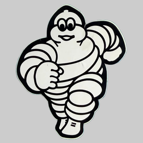 Autocollant publicitaire Michelin représentant Bibendum allongé, silhouette découpée noir et blanc, objet de collection de 8,5 × 7 cm.