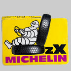Autocollant Michelin ZX vintage avec Bibendum au volant, deux pneus et fond jaune, dimensions 15,7 × 11 cm.