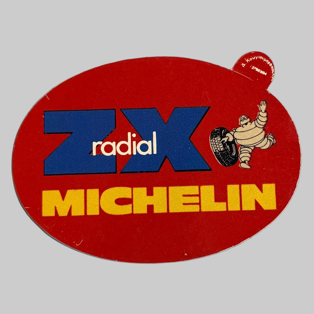 Autocollant publicitaire Michelin ZX Radical rouge avec logo bleu, inscription jaune et Bibendum tenant un pneu.