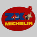 Autocollant publicitaire Michelin ZX Radical rouge avec logo bleu, inscription jaune et Bibendum tenant un pneu.