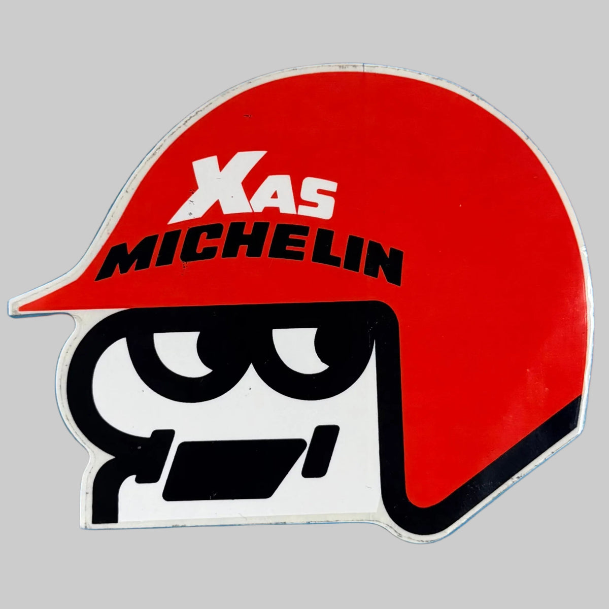 Autocollant vintage Michelin XAS représentant un casque de pilote rouge, dimensions 13,5 × 10,5 cm.