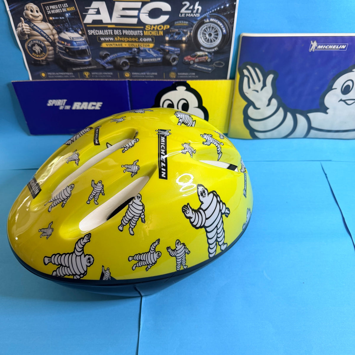 Casque Michelin Bibendum jaune brillant avec aérations et illustrations publicitaires, vue de côté.