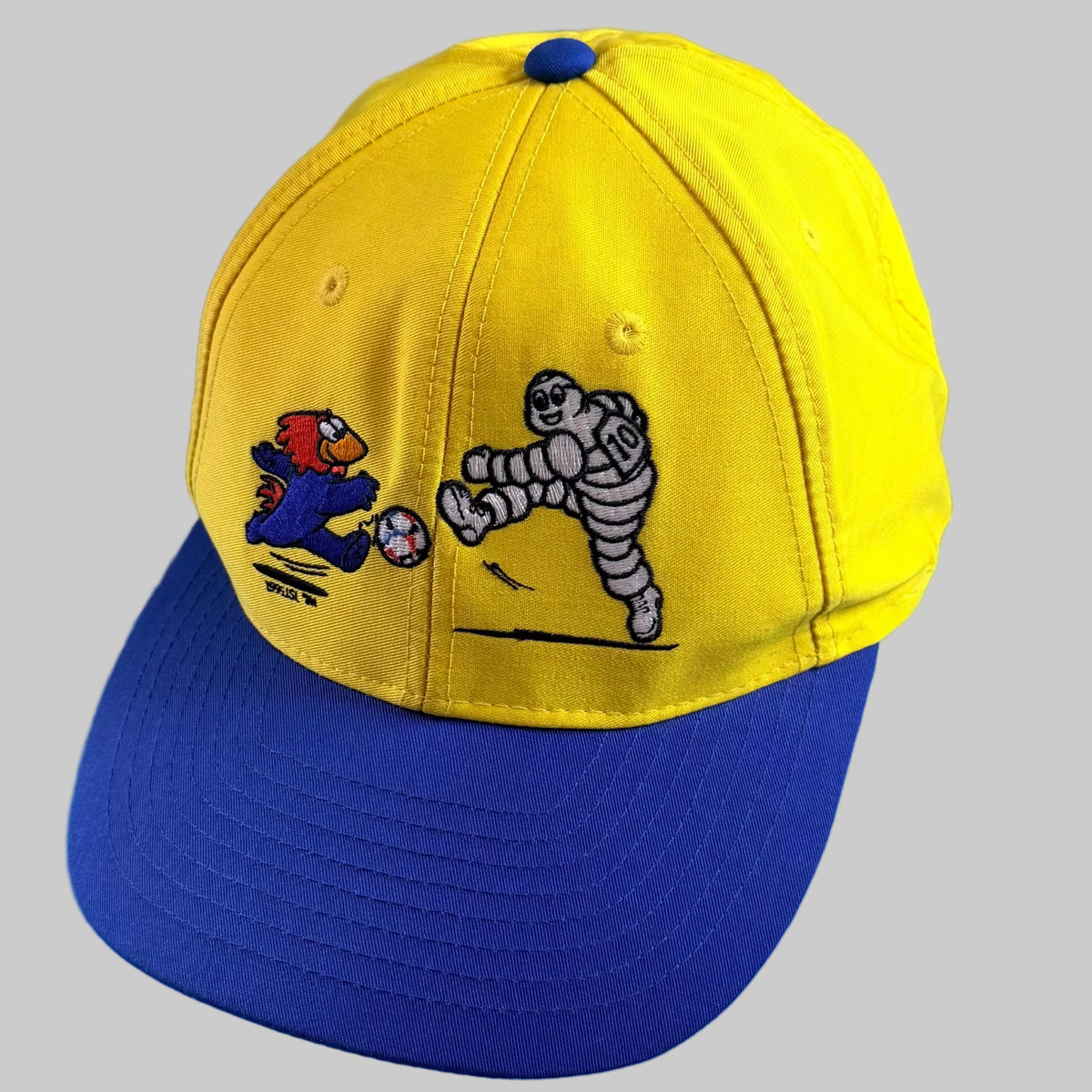 Casquette Michelin France 98 neuve, jaune avec visière bleue, broderies Footix et Bibendum jouant au football sur la face avant.