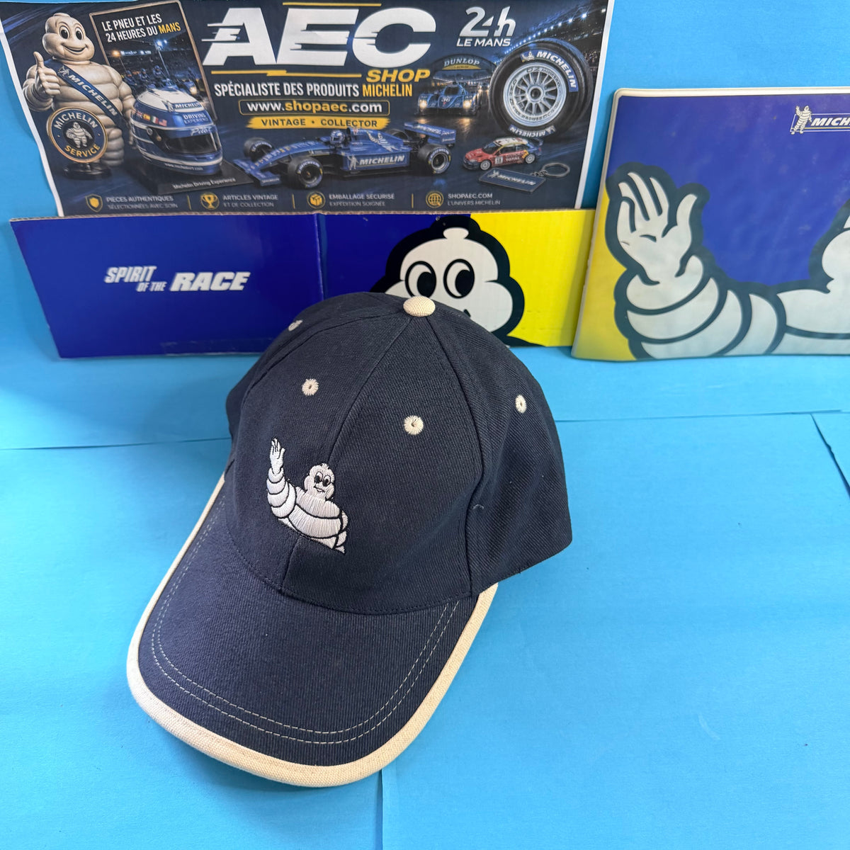 Casquette Michelin Bibendum brodé, vue de trois quarts avec visière incurvée bleu marine et écrue.