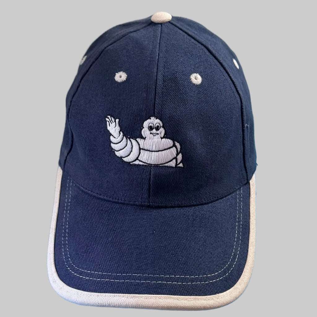 Casquette Michelin bleu marine avec Bibendum blanc brodé et visière bordée d'écru.