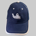 Casquette Michelin bleu marine avec Bibendum blanc brodé et visière bordée d'écru.
