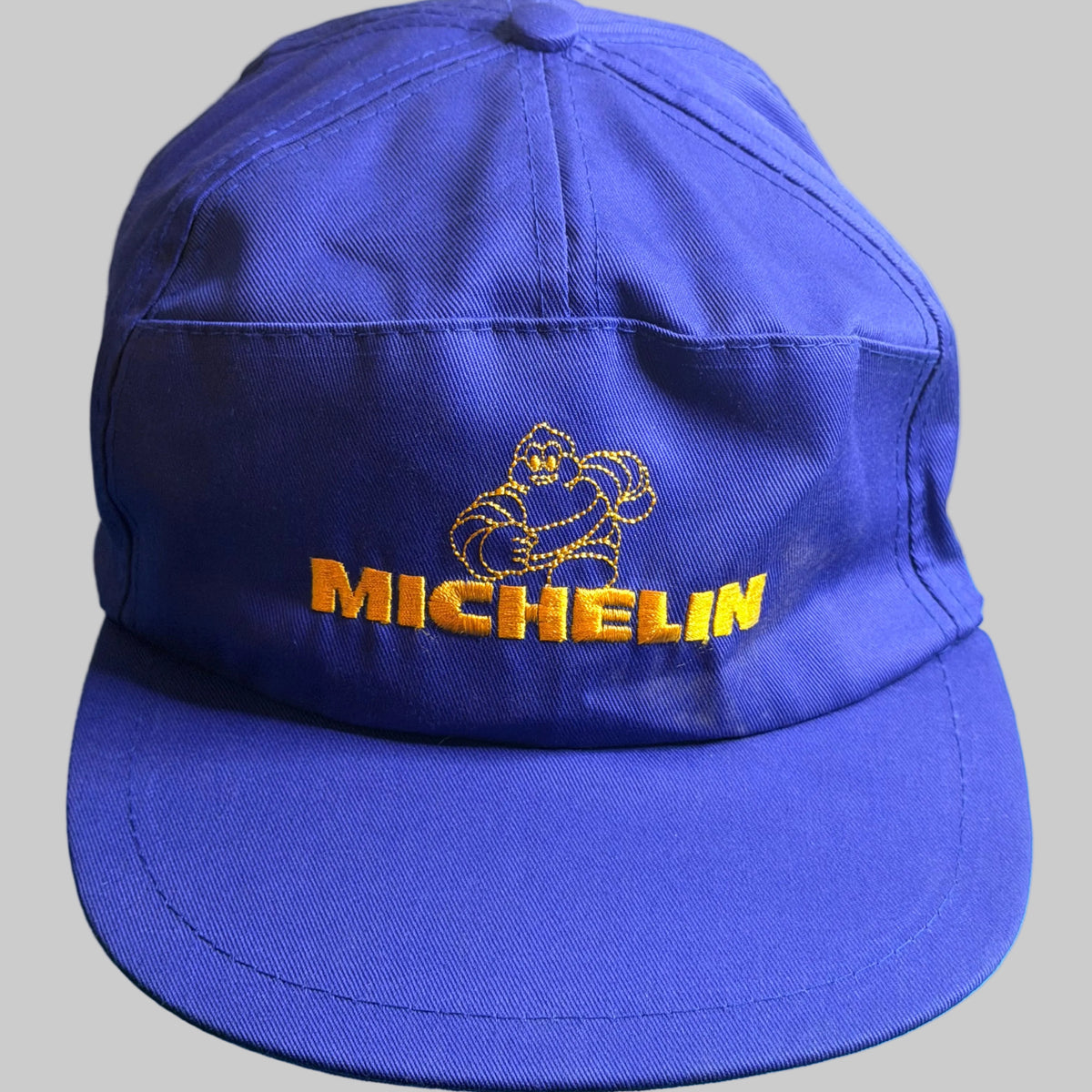 Casquette vintage Michelin bleue avec Bibendum et logo Michelin brodés en jaune. Ancien objet publicitaire de collection en très bel état.