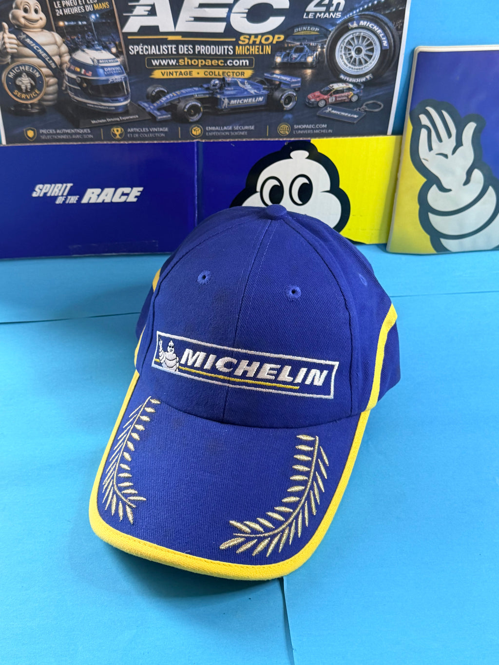 Vue de face casquette Michelin Podium collector bleue et jaune avec lauriers brodés dorés sur la visière