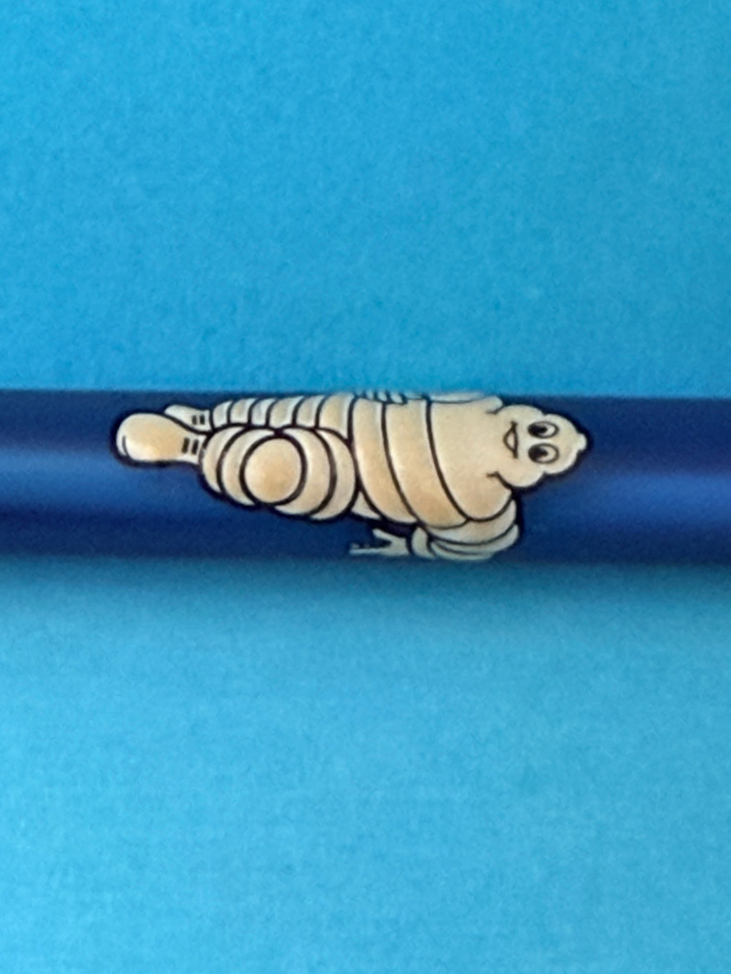  Détail du Bibendum Michelin blanc en relief sur stylo vintage bleu de collection