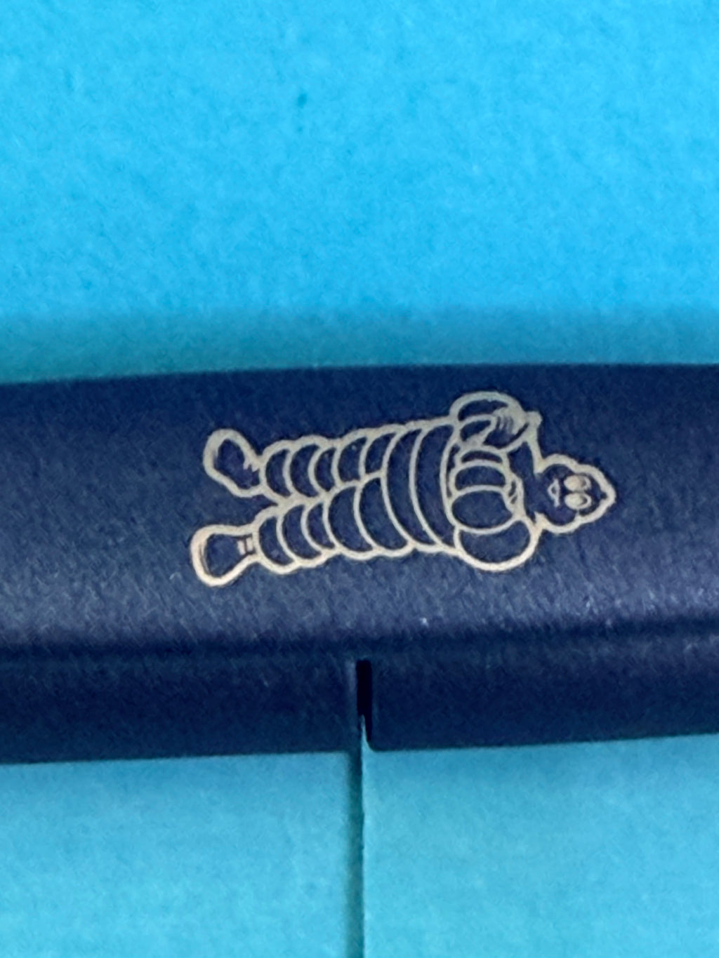 Gros plan sur le Bibendum Michelin imprimé sur le clip du stylo bleu de collection.