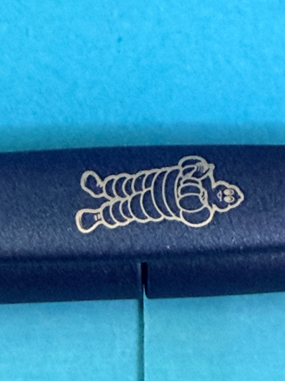 Gros plan sur le Bibendum Michelin imprimé sur le clip du stylo bleu de collection.