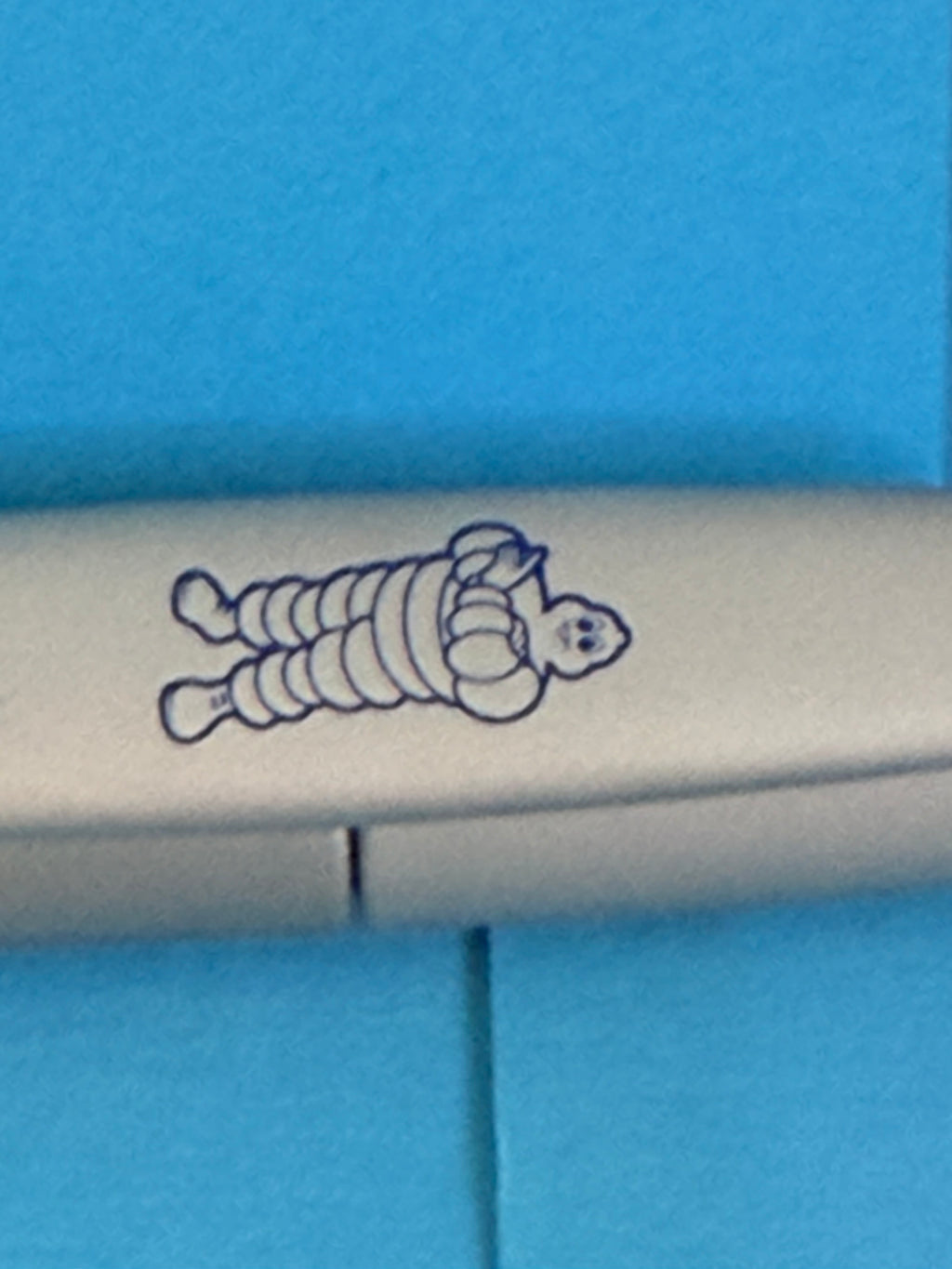 Détail du Bibendum Michelin bleu présent sur le clip du stylo gris de collection.