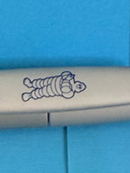 Détail du Bibendum Michelin bleu présent sur le clip du stylo gris de collection.