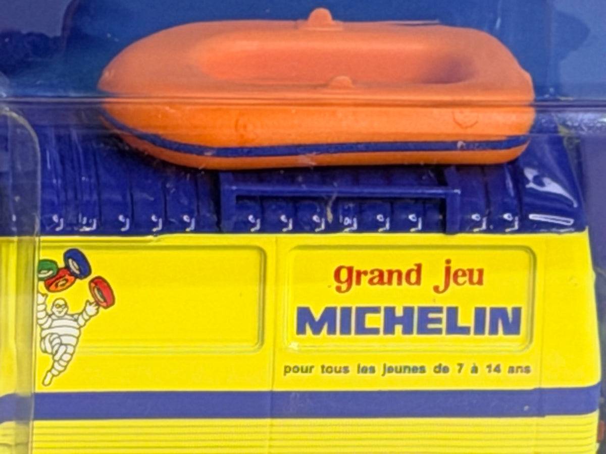 Détail des inscriptions Michelin et du canot de plage sur la miniature Peugeot J7, présentée dans son boîtier transparent.
