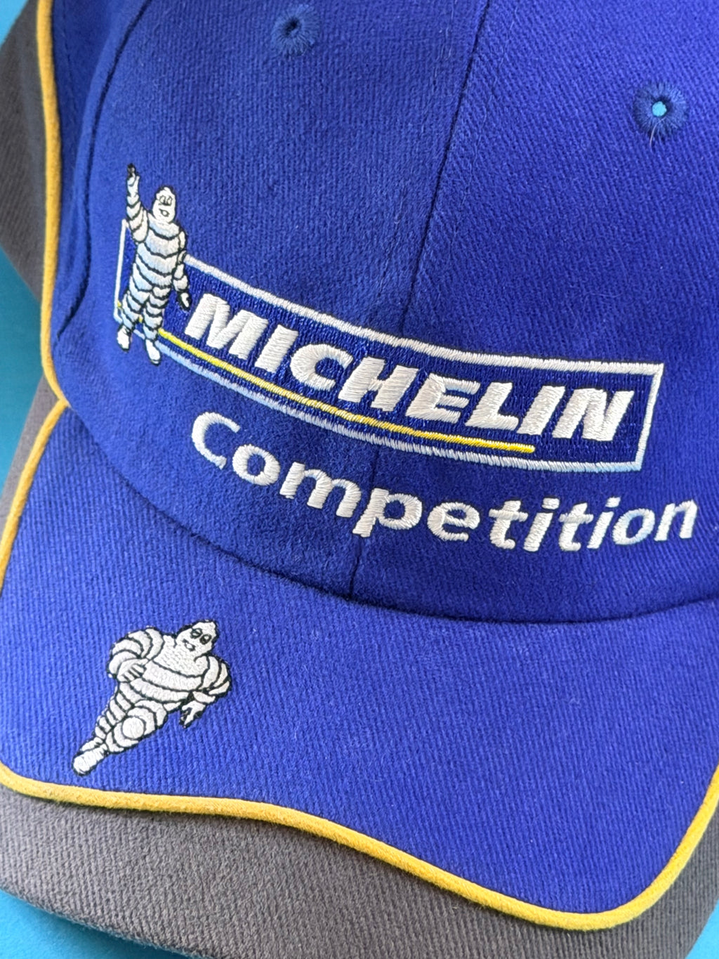 Détail des broderies Michelin Competition et Bibendum sur casquette de collection Michelin bleue.