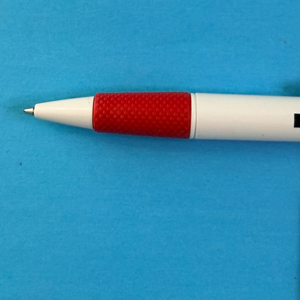 Détail de la pointe et de la zone de préhension rouge texturée du stylo Kleber
