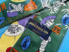 Détail des motifs Bibendum et Michelin sur cravate vintage en soie