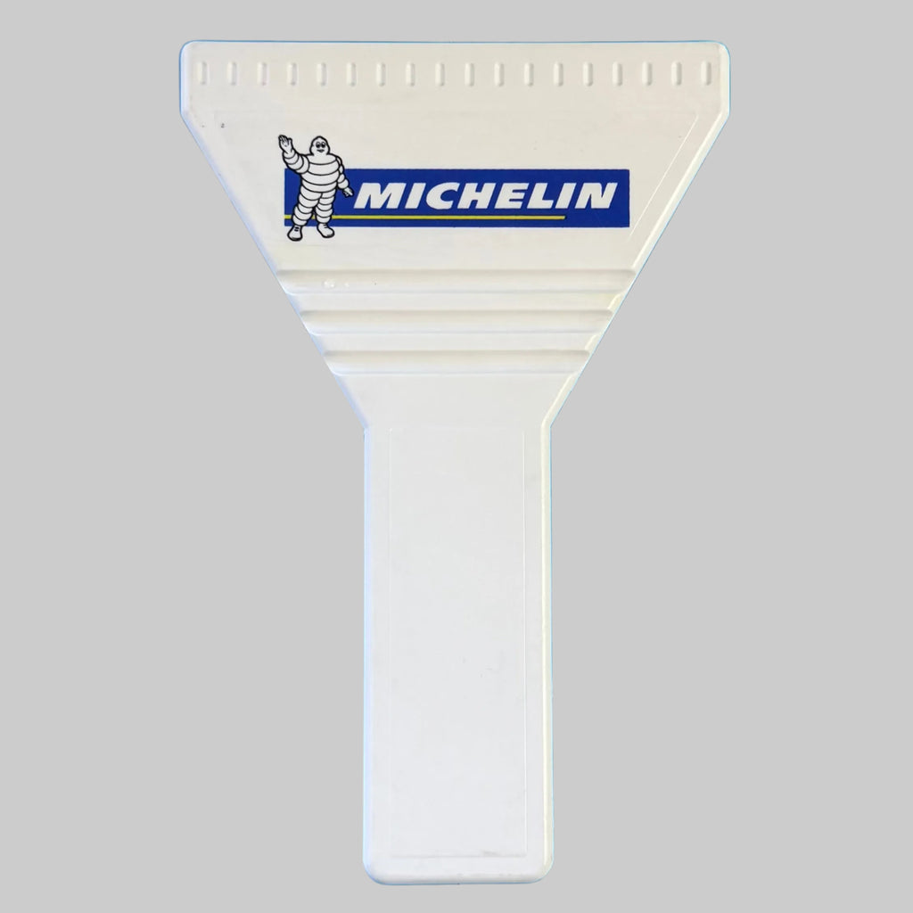 Gratte-pare-brise publicitaire Michelin blanc neuf, avec logo bleu et jaune et représentation de Bibendum sur la partie triangulaire.
