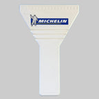 Gratte-pare-brise publicitaire Michelin blanc neuf, avec logo bleu et jaune et représentation de Bibendum sur la partie triangulaire.