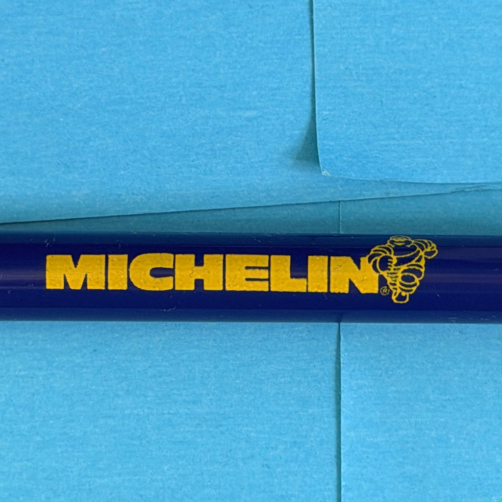 Détail du logo Michelin et du Bibendum jaune sur stylo publicitaire bleu