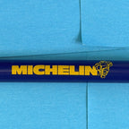 Détail du logo Michelin et du Bibendum jaune sur stylo publicitaire bleu