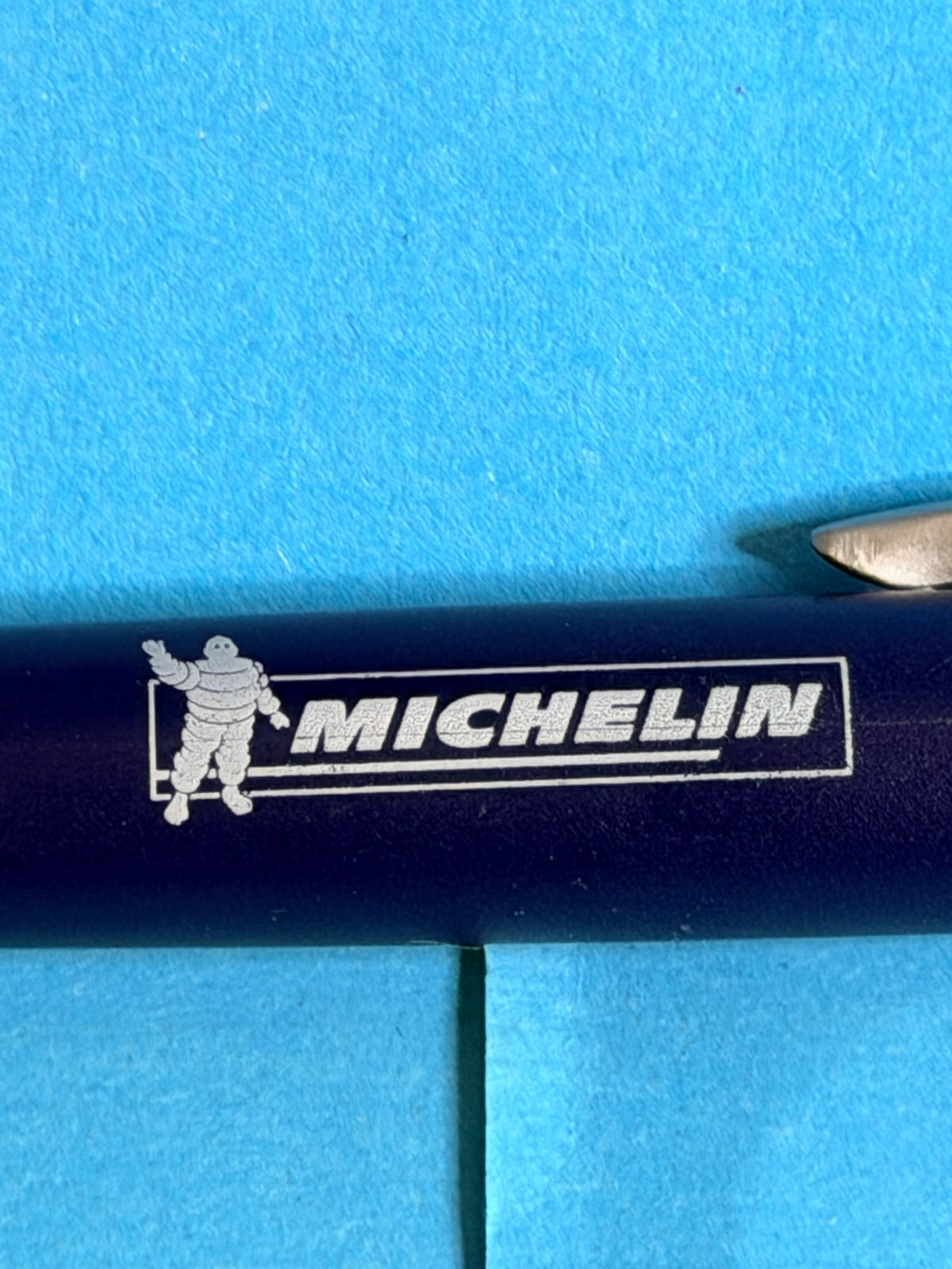 Gros plan du logo Michelin et de Bibendum sur stylo publicitaire bleu de collection