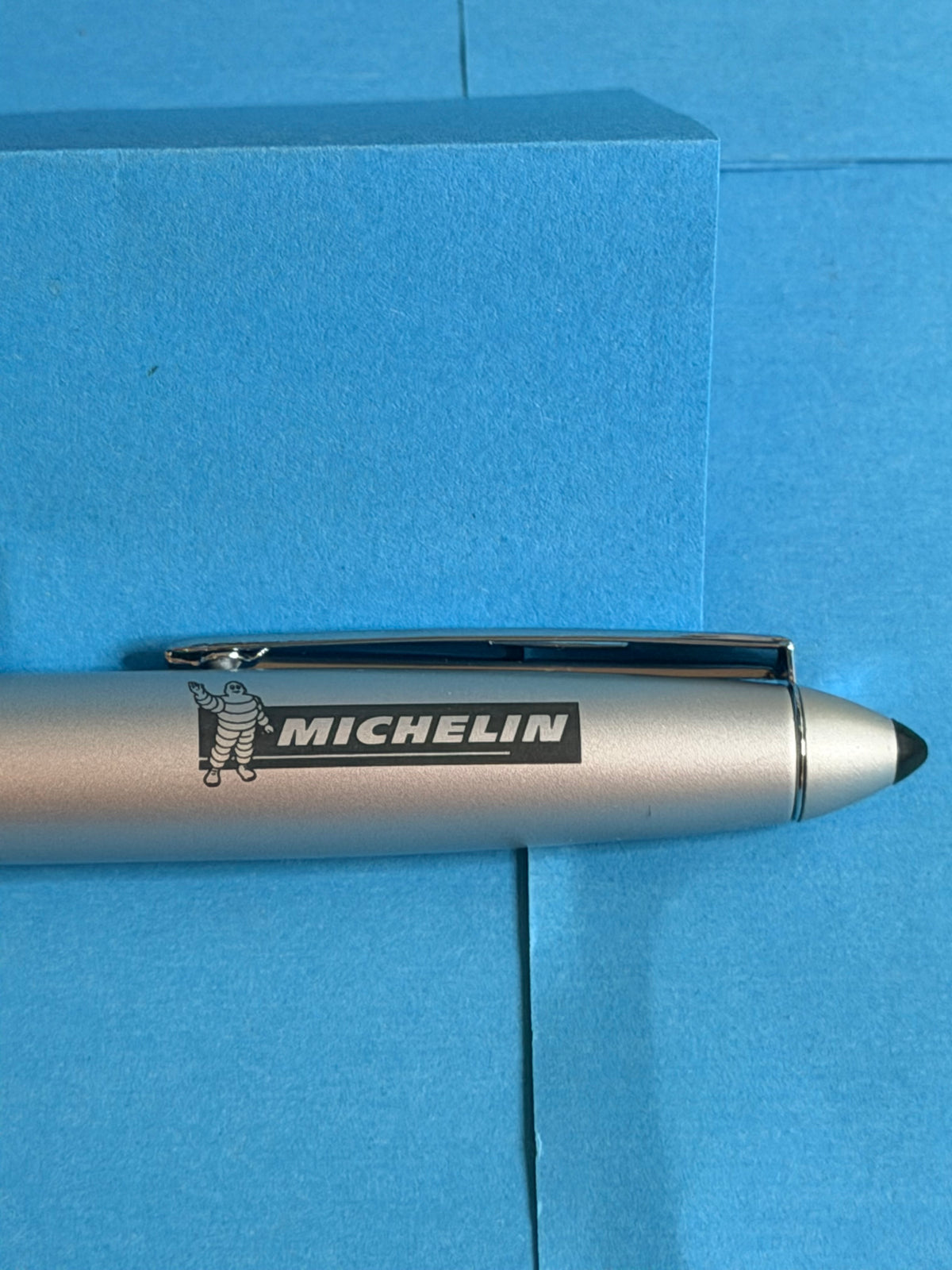 Vue complète du stylo Michelin argenté avec grip noir, finitions chromées et logo Bibendum.
