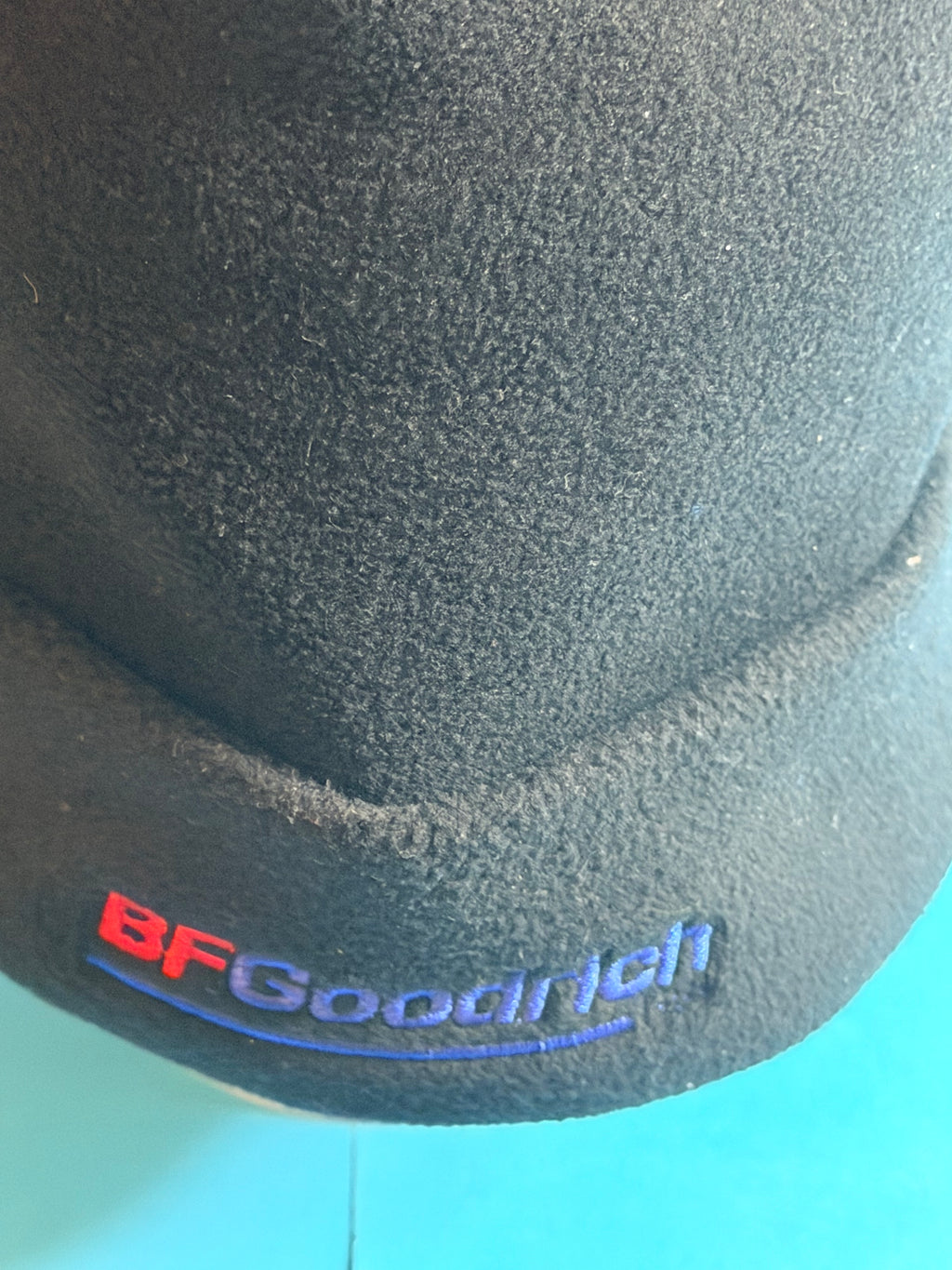 Gros plan sur le logo BFGoodrich brodé rouge et bleu sur le bonnet polaire noir.