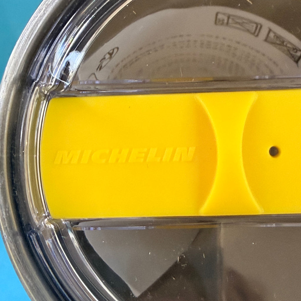 Gros plan sur le système d'ouverture jaune du mug isotherme Michelin avec inscription de la marque.