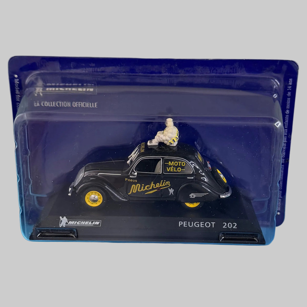 Miniature Peugeot 202 Michelin de collection présentée dans son boîtier transparent de protection, vue de trois quarts du véhicule.