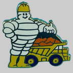 Pin’s Michelin Bibendum ouvrier avec casque jaune et camion-benne de chantier, vue de face
