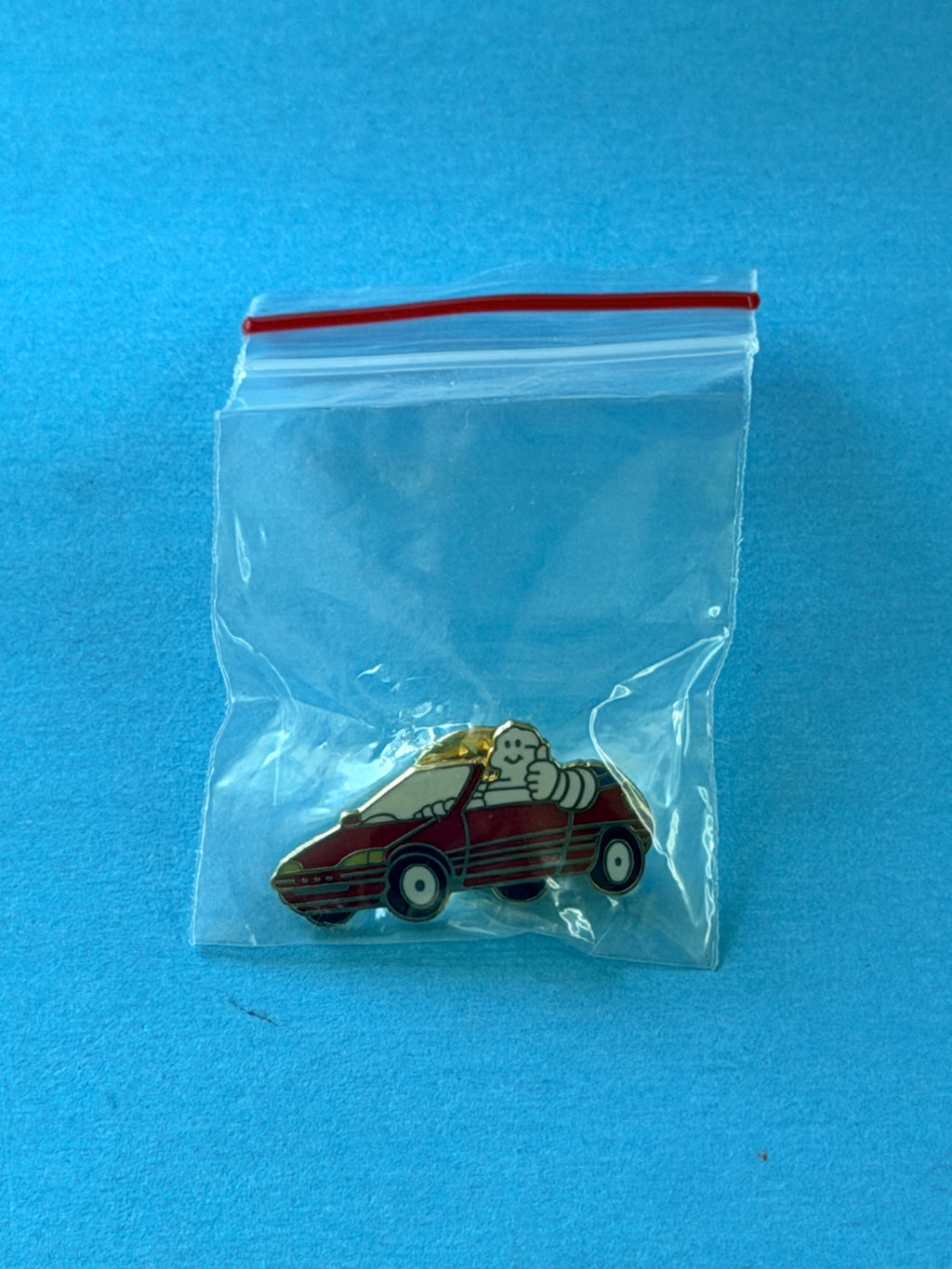 Pin’s Michelin Bibendum cabriolet rouge présenté dans son sachet plastique de protection