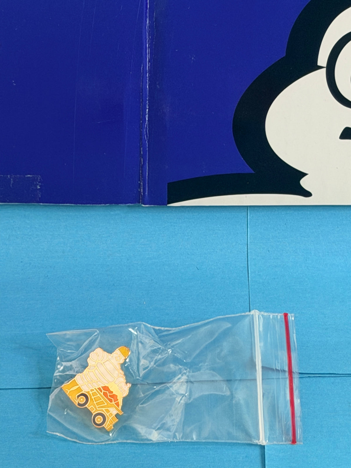 Pin’s Michelin Bibendum ouvrier et engin de chantier présenté sous sachet plastique de protection