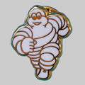 Gros plan du pin’s Michelin Bibendum en métal émaillé blanc et doré – fabrication Fraisse Paris