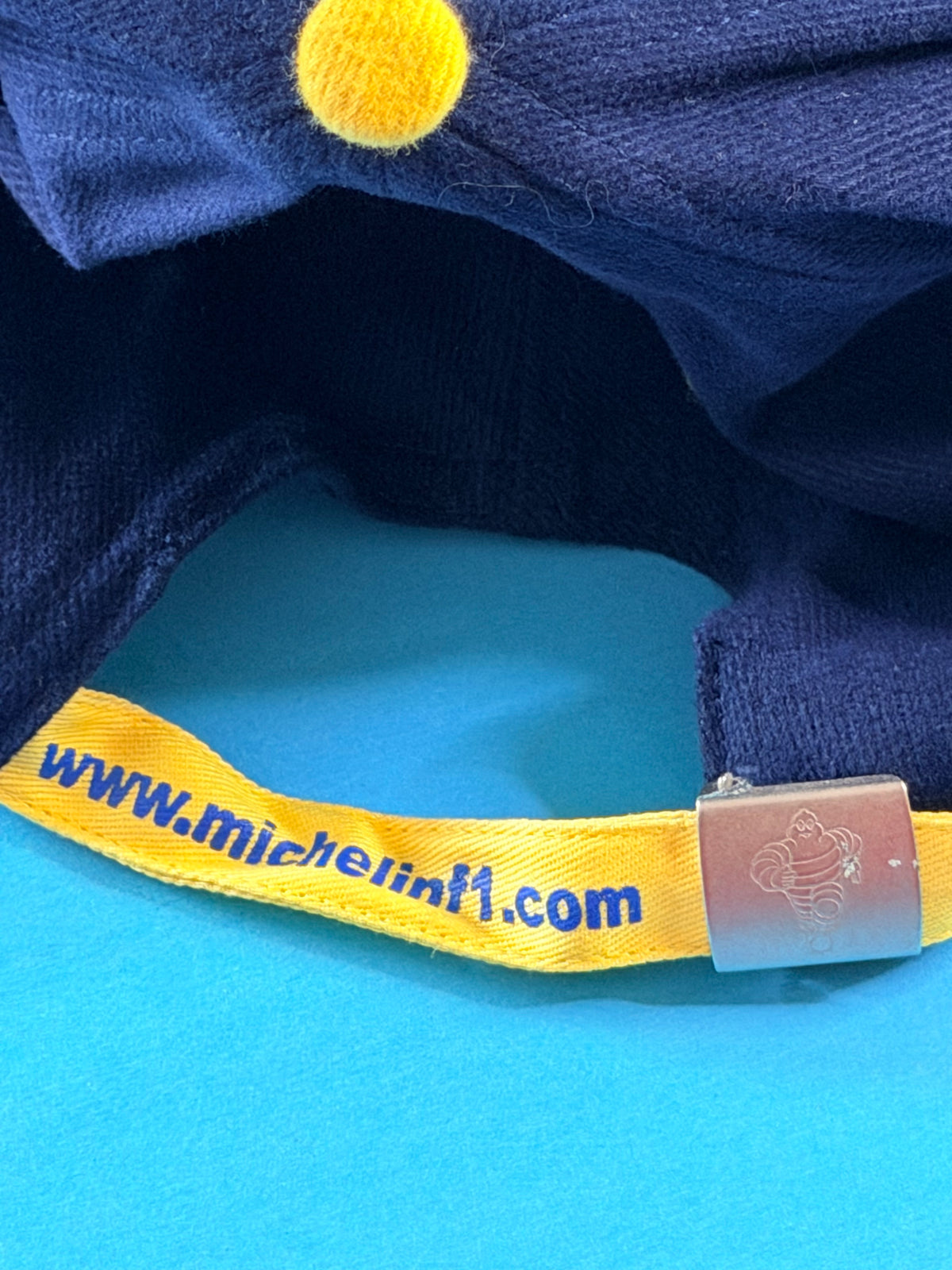 Sangle arrière jaune http://www.michelinf1.com et boucle métallique Bibendum de la casquette Michelin F1.