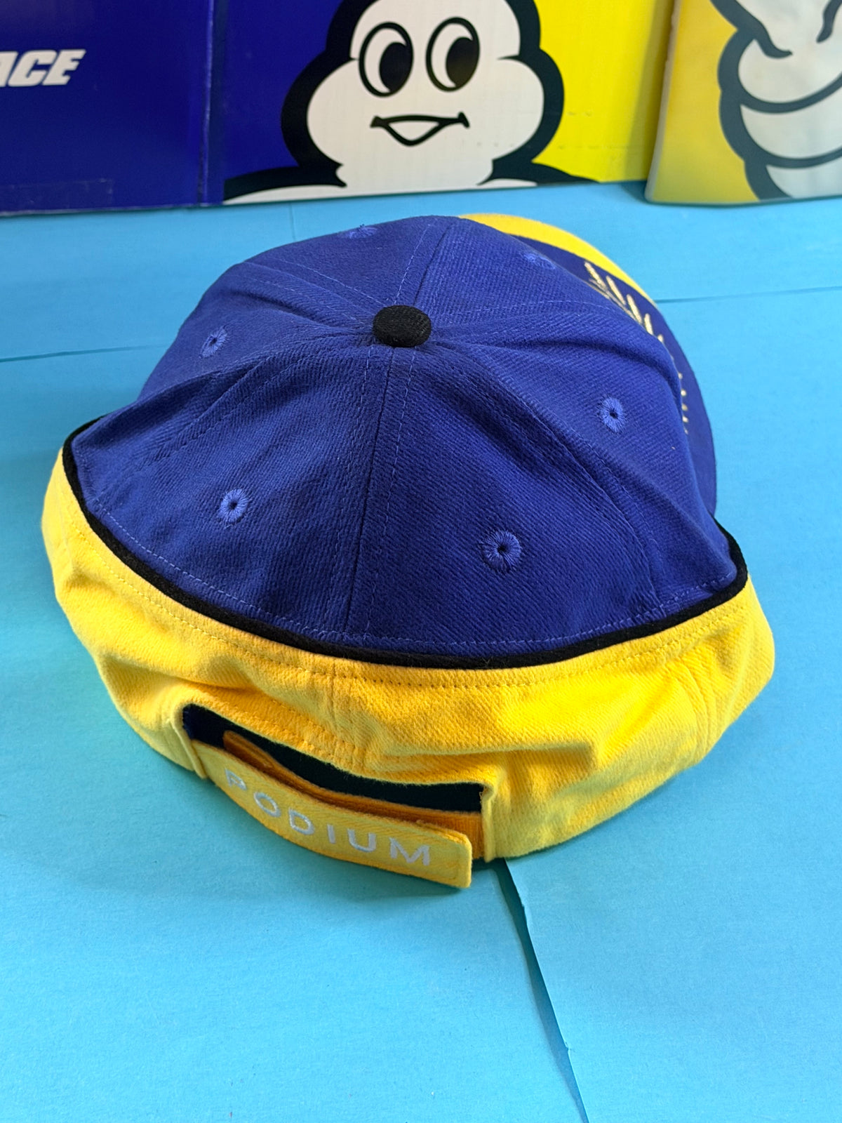 Vue arrière de la casquette Michelin Podium bleue et jaune avec patte de réglage brodée PODIUM