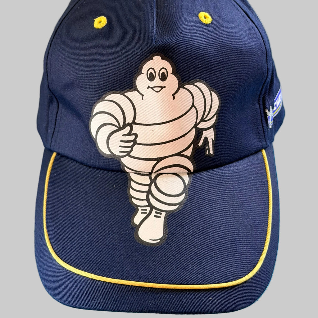 Casquette Michelin Formula F1 neuve bleu marine avec grand Bibendum sur l’avant et liseré jaune sur la visière.