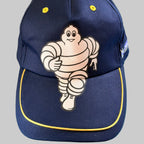 Casquette Michelin Formula F1 neuve bleu marine avec grand Bibendum sur l’avant et liseré jaune sur la visière.