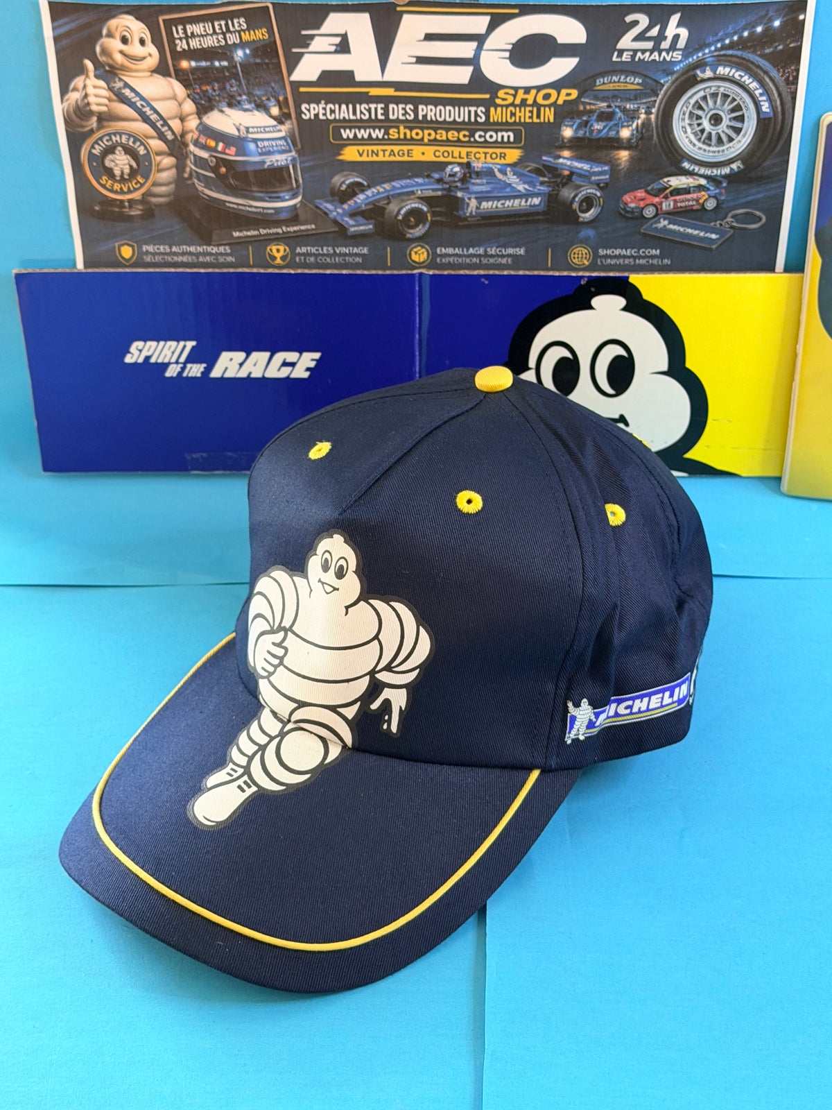 Vue trois-quarts de la casquette Michelin F1 Bibendum neuve bleu marine avec détails jaunes et logo latéral Michelin.