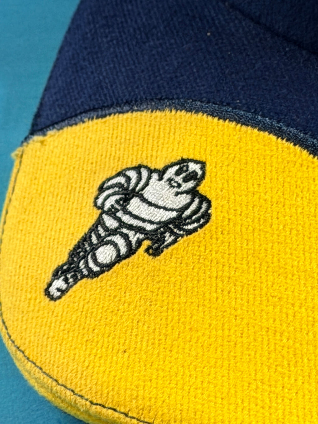 Détail du Bibendum Michelin brodé sur la visière jaune de la casquette Formula 1.